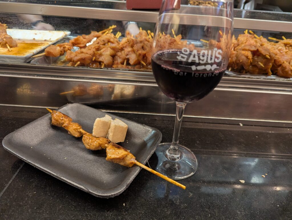 Bar Lorenzo名物の熱々な豚肉のマリネ串焼き（Pinchito）とグラスワイン