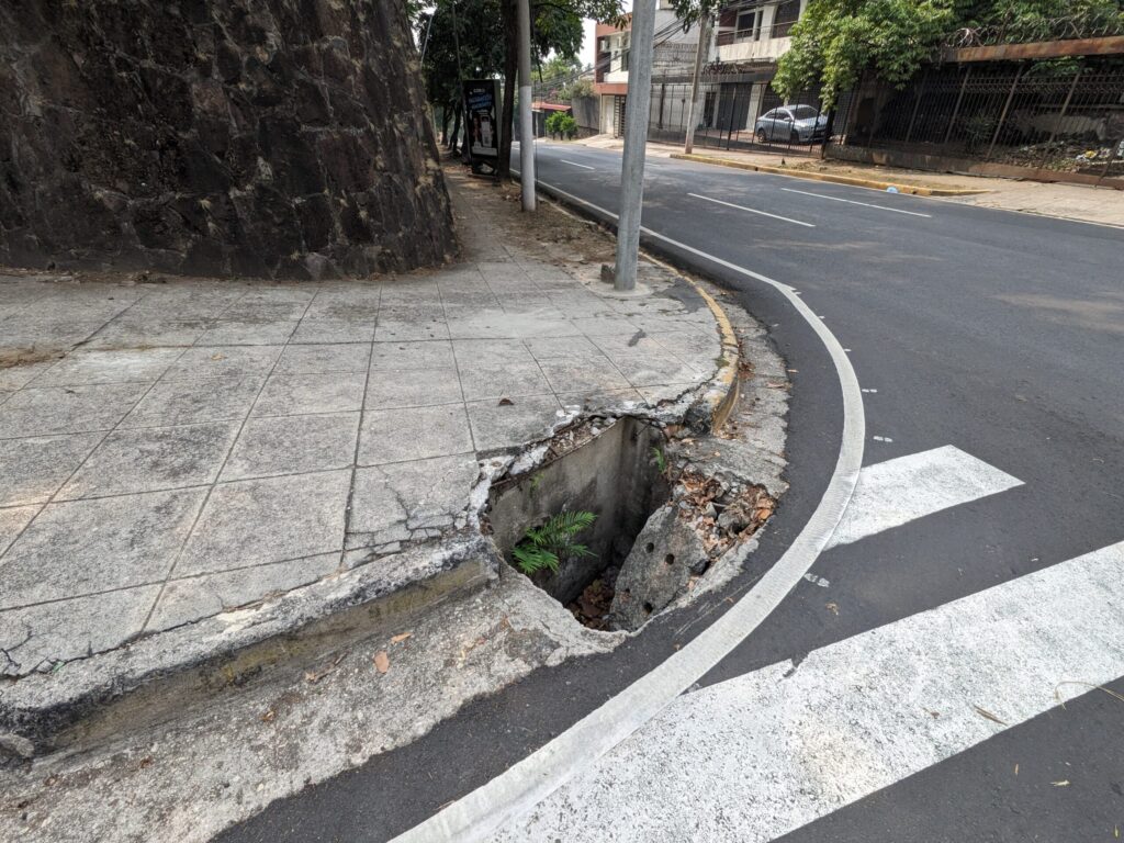 エルサルバドルの歩道と道路の間にある排水溝のふたが壊れて穴が露出している様子